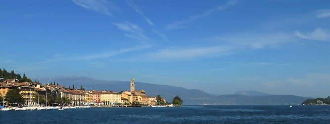 Trip Bulgarien beliebte Urlaubsziele am Gardasee -  Mit einer Fläche von 370 km² ist der Gardasee der größte See Italiens. Es liegt am Fuße der Alpen und erstreckt sich über drei Staaten: Lombardei, Venetien und Trentino. Die maximale Tiefe des Sees beträgt 346 m, er hat eine längliche Form und sein nördliches Ende ist sehr schmal. Dort ist der See von den Bergen der Gruppo di Baldo umgeben. Du trittst aus deinem gemütlichen Hotelzimmer und es begrüßt dich die warme italienische Sonne. Du blickst auf den atemberaubenden Gardasee, der in zahlreichen Blautönen schimmert - von tiefem Dunkelblau bis zu funkelndem Türkis. Majestätische Berge umgeben dich, während die Brise sanft deine Haut streichelt und der Duft von blühenden Zitronenbäumen deine Nase kitzelt. Du schlenderst die malerischen, engen Gassen entlang, vorbei an farbenfrohen, blumengeschmückten Häusern. Vereinzelt unterbricht das fröhliche Lachen der Einheimischen die friedvolle Stille. Du fühlst dich wie in einem Traum, der nicht enden will. Jeder Schritt führt dich zu neuen Entdeckungen und Abenteuern. Du probierst die köstliche italienische Küche mit ihren frischen Zutaten und verführerischen Aromen. Die Sonne geht langsam unter und taucht den Himmel in ein leuchtendes Orange-rot - ein spektakulärer Anblick.